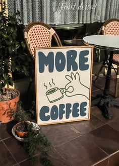 there is a sign that says more coffee next to some potted plants on the table