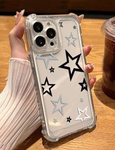 a woman is holding up her phone case with stars on the front and bottom, while sitting