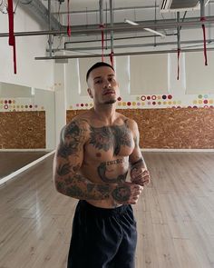 a man with tattoos standing in an empty room