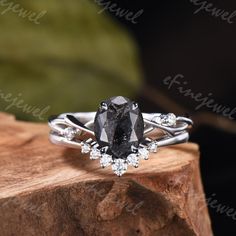 a black and white diamond ring sitting on top of a piece of wood