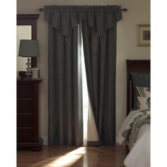 a bed room with a neatly made bed and a window covered in gray drapes