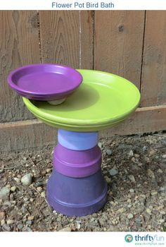 purple and green plates stacked on top of each other in front of a wooden fence