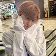 a young man sitting on an escalator with his arms wrapped around his head