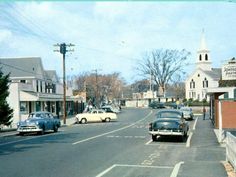 an old photo of cars driving down the street