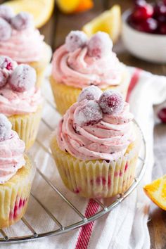 cupcakes with pink frosting and cranberries on a cooling rack