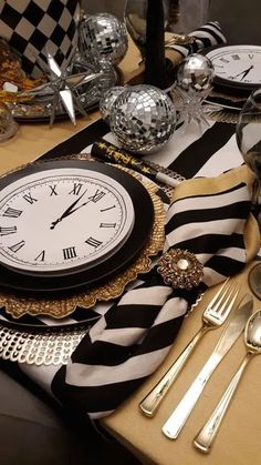 a table topped with lots of silverware and a clock on it's side