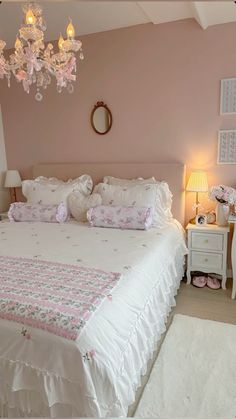 a white bed sitting in a bedroom under a chandelier