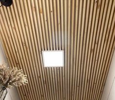 a bathroom with a toilet, sink and wood paneled walls on the ceiling above it