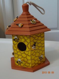 a yellow bird house with bees on it