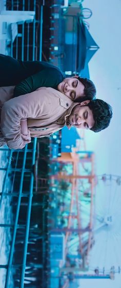 two people standing next to each other in front of a tall building with lights on it