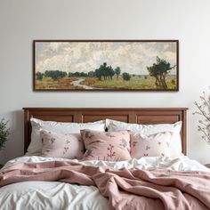 a bed with pillows and blankets on top of it in front of a wall mounted painting