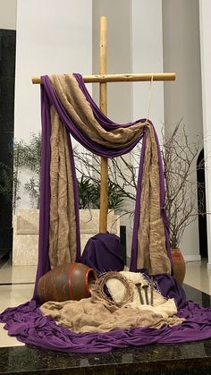 an altar with purple and gold cloth draped over it, next to a wooden cross