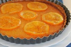 there is a pie with orange slices in it on the plate next to a cupcake tin