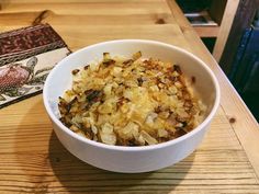 a white bowl filled with food on top of a wooden table