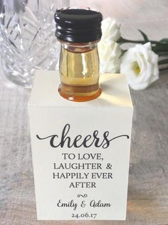 a small bottle filled with honey sitting on top of a table next to white flowers