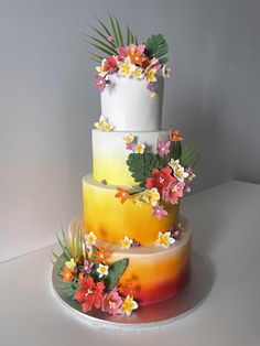 a three tiered cake with flowers and leaves on the top is painted yellow, pink, orange and white