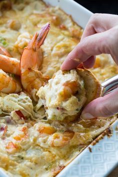 a person dipping shrimp into a casserole dish