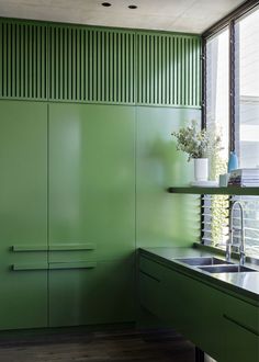 a kitchen with green painted walls and cabinets in the corner, next to a sink