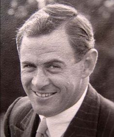 an old black and white photo of a man in a suit smiling at the camera