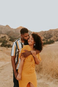 a man and woman hugging each other in the desert