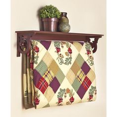 a wooden shelf with two potted plants on it and a quilt hanging from the wall