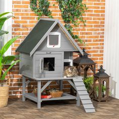 a cat house with two cats in it on the floor next to a brick wall