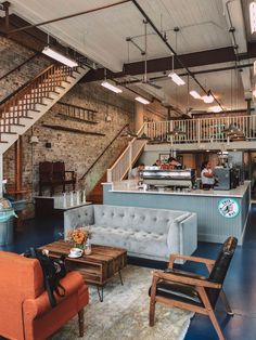 a living room filled with furniture next to a kitchen and staircase leading up to the second floor