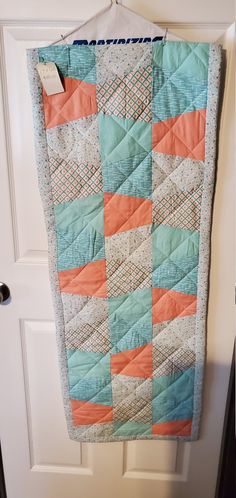 a blue and orange quilt hanging on a door hanger in front of a white door