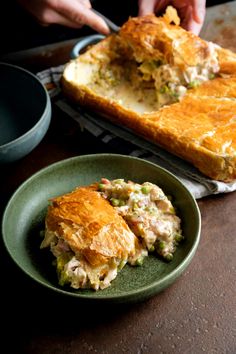 someone is taking a slice of chicken pot pie from a green plate on the table