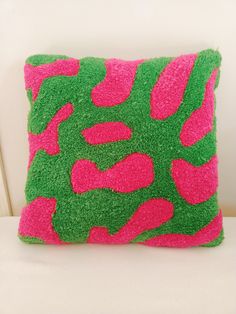 a pink and green pillow sitting on top of a white couch