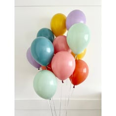 a bunch of balloons are in a vase on the floor next to a white wall