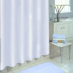 a white shower curtain in a bathroom next to a bathtub and sink with blue rugs on the floor