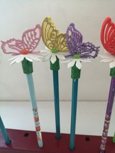 four pencils are decorated with butterflies and daisies