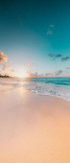 the sun is setting on an empty beach with white sand and blue ocean water in the foreground