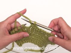 two hands crocheting the ends of a piece of green yarn on a glass plate