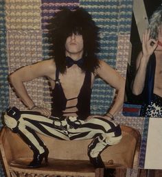 a man with long hair sitting on top of a wooden chair next to a wall