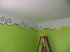 a ladder is in front of a green wall with black swirls painted on it