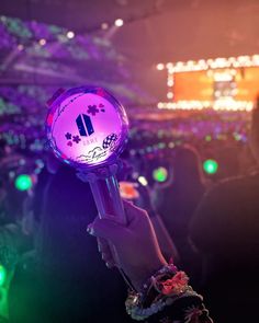 a person holding up a purple light at a concert