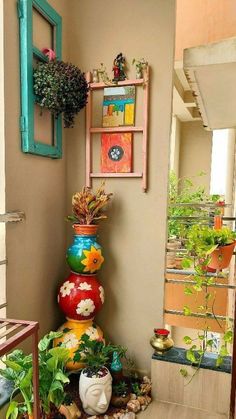 colorful pots are stacked on top of each other in front of a wall with plants