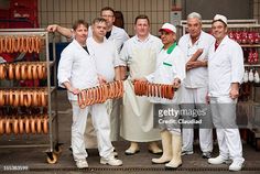 group of men in white uniforms holding sausages