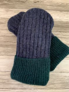 two mittens sitting on top of a wooden floor next to each other, one green and the other gray