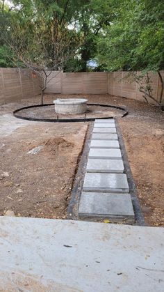 a stone path in the middle of a yard with trees and fence around it,