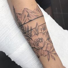 a woman's arm with flowers and mountains in the background on her left forearm