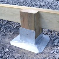 a piece of wood sitting on top of a pile of gravel next to a wooden post