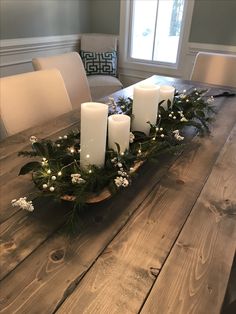 a wooden table topped with candles and greenery