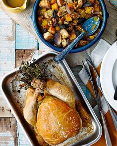 a roasting pan filled with chicken, potatoes and carrots next to a bowl of stuffing