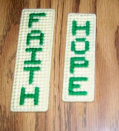 two green and white magnets on a wooden table with the word faith written in small letters