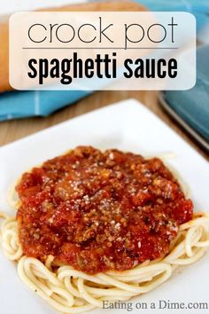 a white plate topped with spaghetti sauce on top of a wooden table next to bread