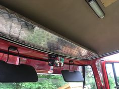 the interior of a truck with its bed up and windows open, showing trees in the background