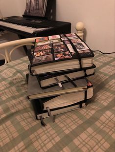 a stack of books sitting on top of a bed next to a black piano keyboard